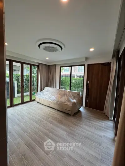 Spacious living room with large windows and garden view, featuring modern flooring and elegant ceiling design.
