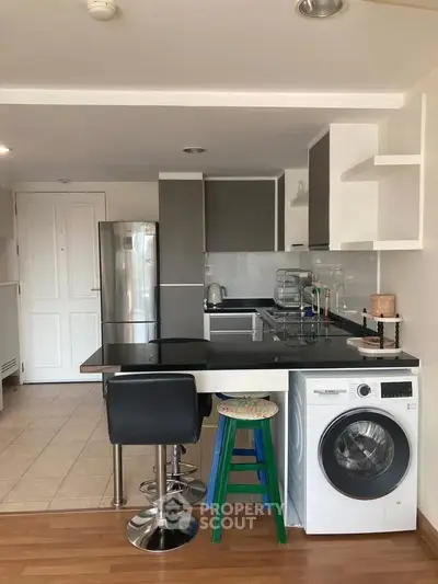 Modern kitchen with sleek appliances and breakfast bar in stylish apartment.