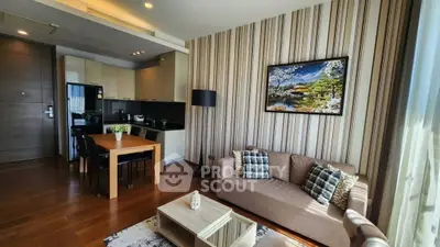 Modern living room with stylish decor and open kitchen layout, featuring elegant wooden flooring and natural light.