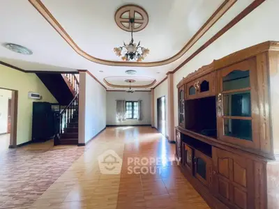 Spacious living room with elegant wooden furniture and staircase in a stylish home.