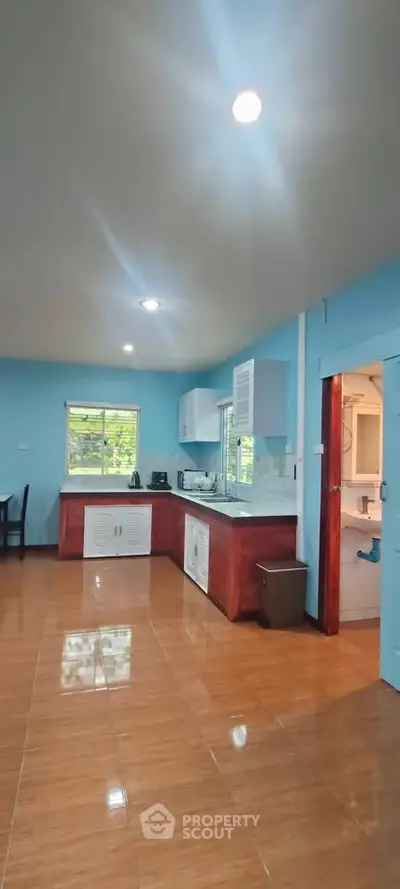 Spacious kitchen with modern appliances and wooden flooring in a bright blue interior.