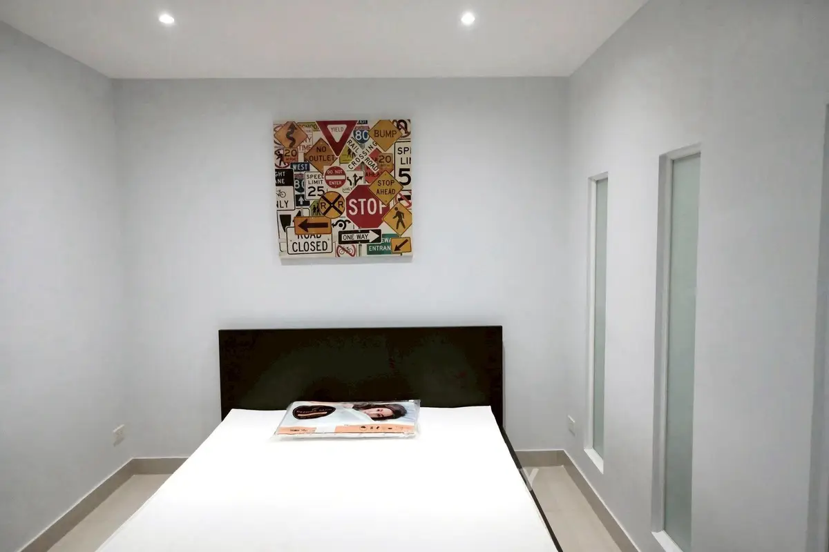 Modern bedroom with minimalist decor and unique traffic sign artwork on the wall.