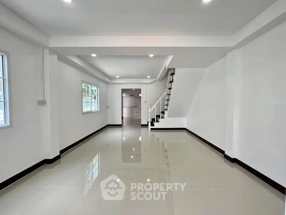 Spacious open-plan living area with modern staircase and large windows.