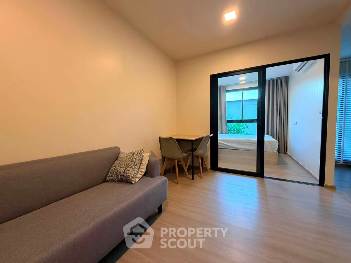 Modern living room with cozy sofa and dining area leading to a bedroom