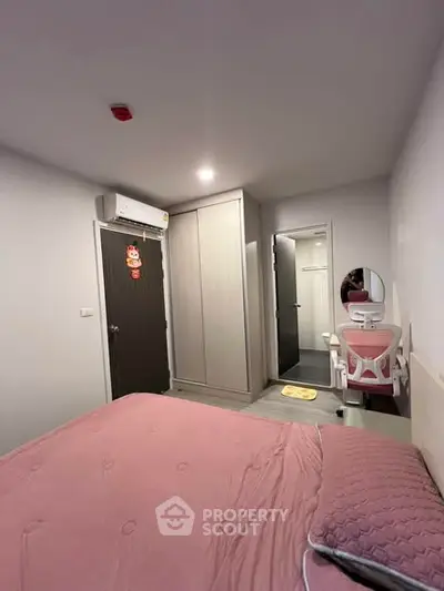 Cozy bedroom with pink bedding, wardrobe, and modern vanity setup.