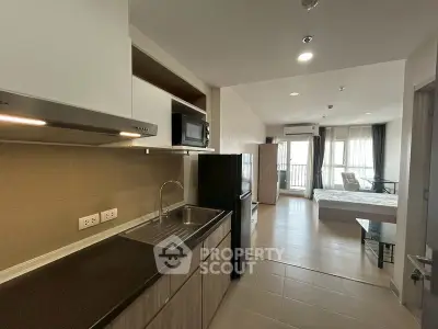 Modern open-plan studio apartment with sleek kitchen and spacious living area.