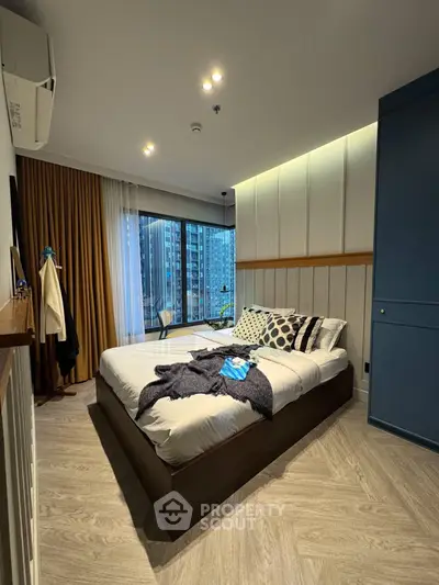 Modern bedroom with city view, featuring stylish decor and large windows for natural light.