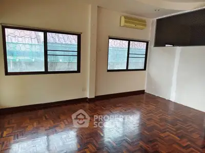 Spacious empty room with parquet flooring and large windows, ideal for customization.
