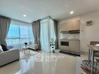 Modern open-layout living room with kitchen, featuring large windows and stylish decor.