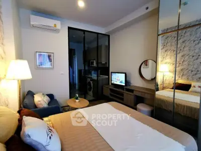 Modern bedroom with mirrored wardrobe and cozy seating area in stylish apartment.