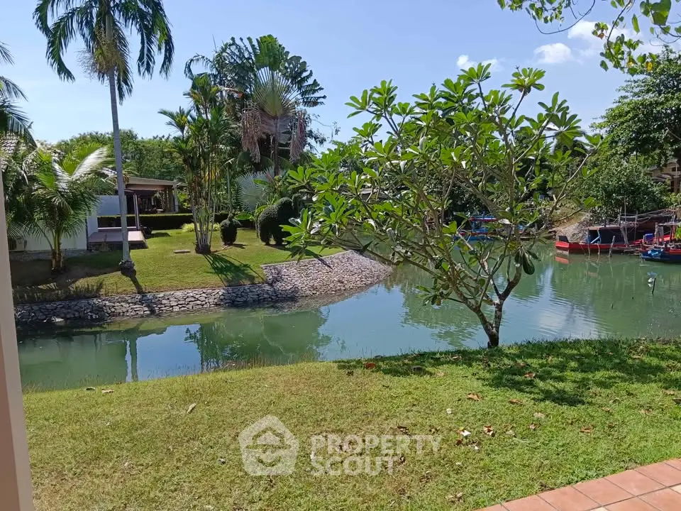 Serene garden view with lush greenery and tranquil waterway in a tropical setting.