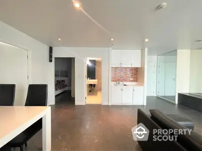 Spacious modern open-plan living area with sleek white kitchen, ample lighting, and polished floors, ideal for entertaining and comfortable living.