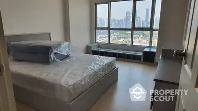 Spacious bedroom with large windows offering a panoramic city view, featuring a modern design and ample natural light.