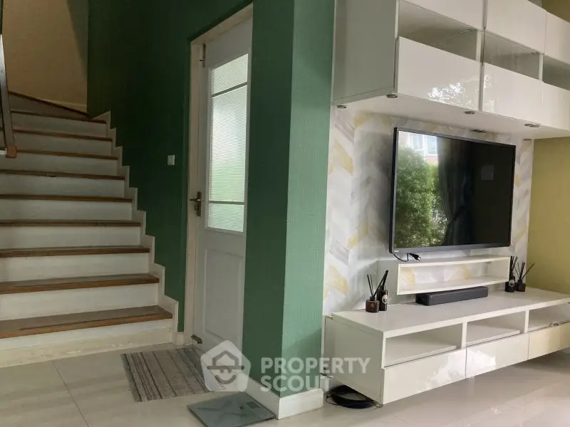 Modern living room with stylish TV setup and elegant staircase