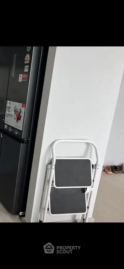 Modern kitchen corner with sleek refrigerator and folding step ladder.