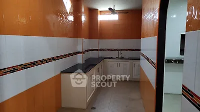 Spacious kitchen with vibrant orange and white tiles, featuring a sleek countertop and ample storage.