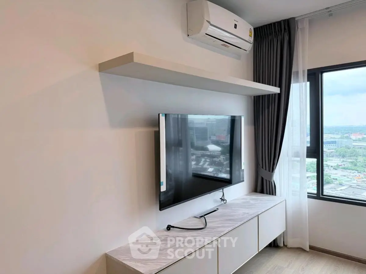 Modern living room with wall-mounted TV and air conditioning, offering a city view.