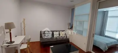 Modern living room with sleek furniture and adjacent bedroom view.