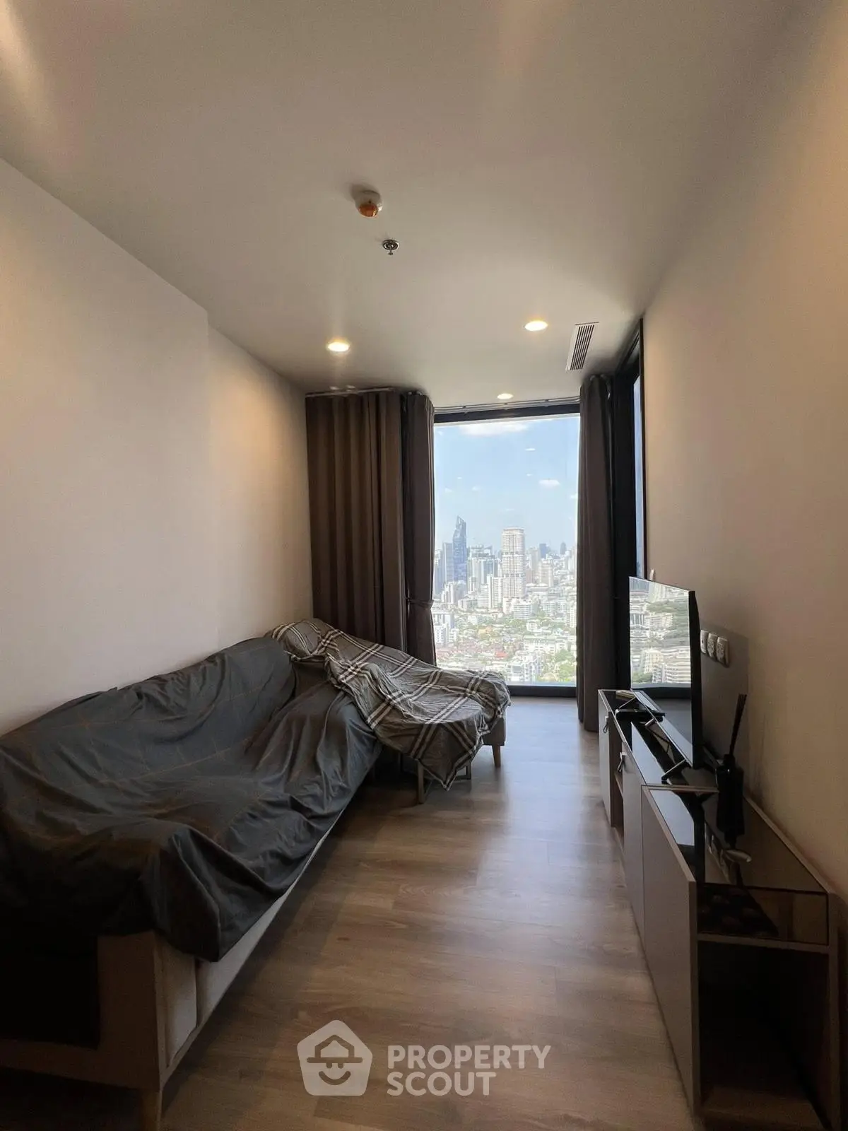 Modern living room with city view, featuring sleek furniture and large windows for natural light.