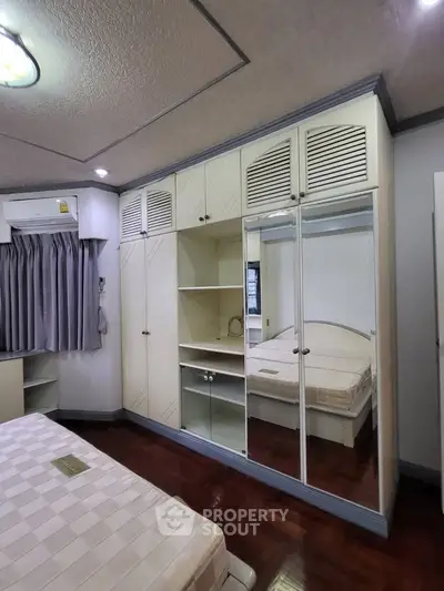 Spacious bedroom with built-in mirrored wardrobe and elegant ceiling design.