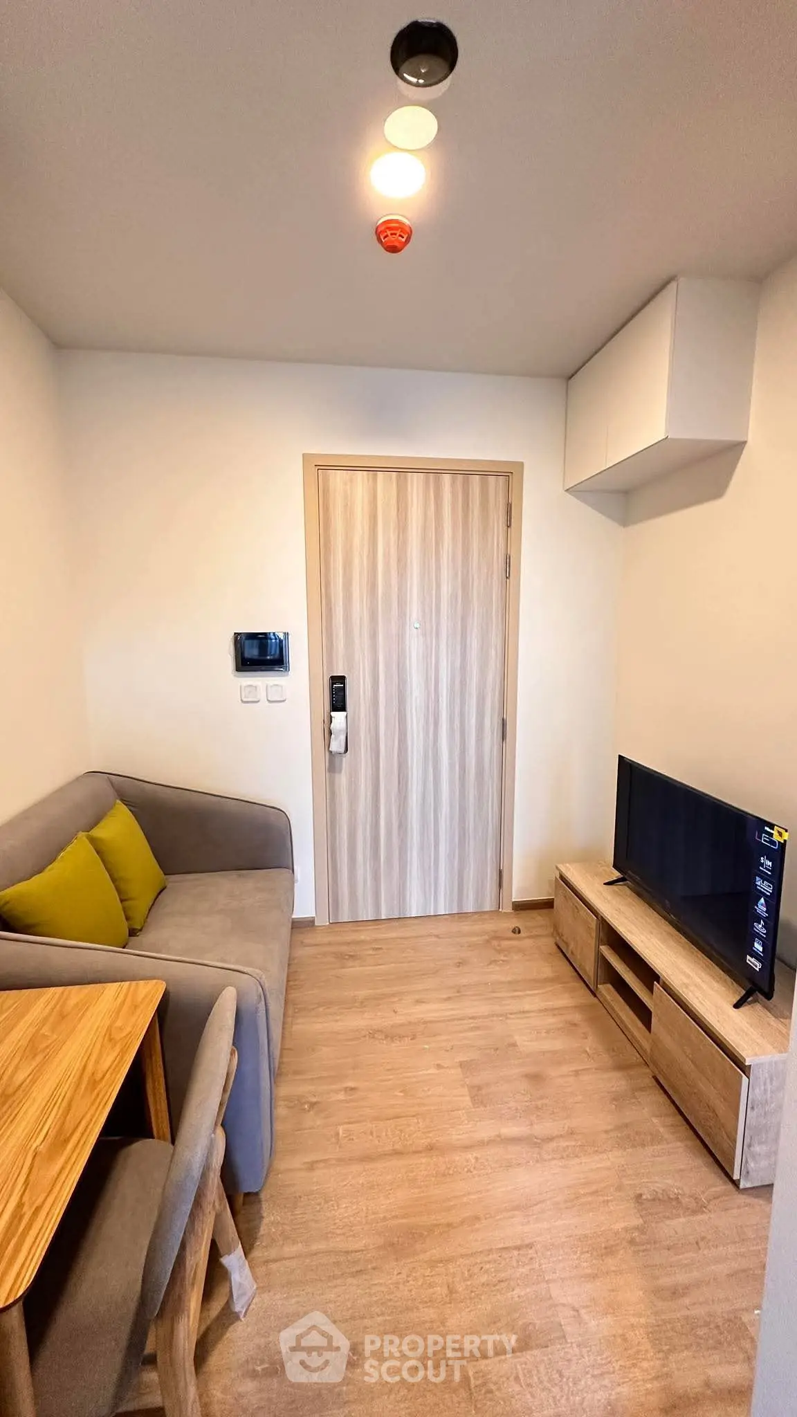 Cozy living room with modern furniture and wooden flooring in a compact apartment.