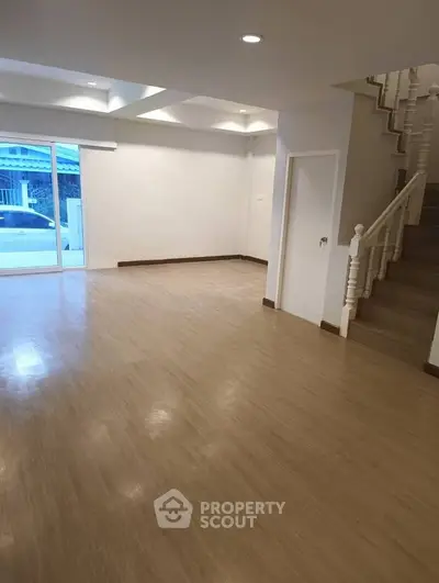 Spacious open-plan living room with wooden flooring and staircase, ideal for modern family living.