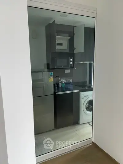 Modern compact kitchen with appliances including washing machine and microwave.