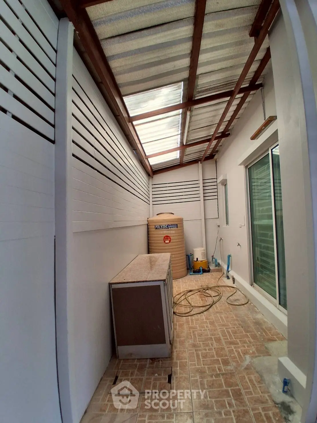 Spacious outdoor utility area with covered roof and tiled flooring, perfect for storage or laundry setup.