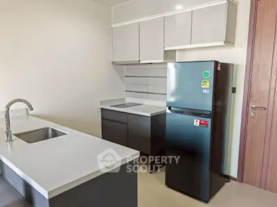Modern kitchen with sleek cabinetry and stainless steel fridge in a contemporary apartment.