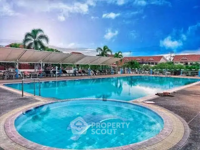 Stunning residential pool area with clear blue water and palm trees, perfect for relaxation.