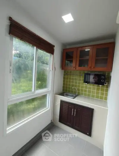 Compact kitchen with green tile backsplash and wooden cabinets