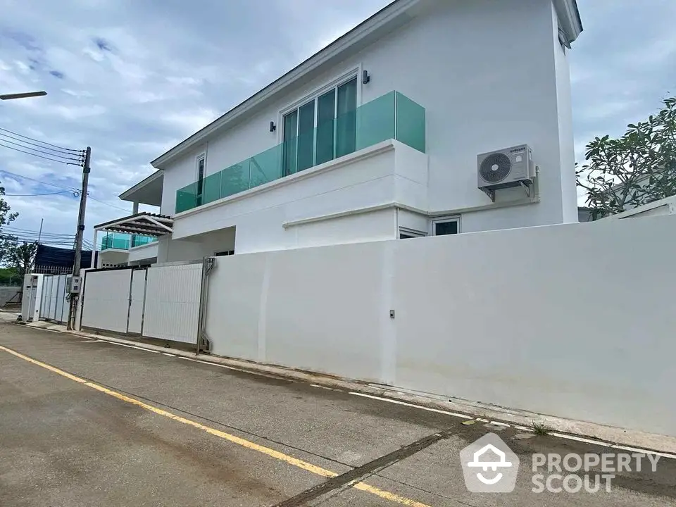 Modern white two-story house with glass balcony and air conditioning unit