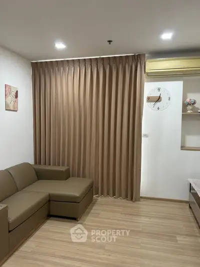 Modern living room with sleek brown sofa and elegant curtains, featuring a wall clock and minimalist decor.
