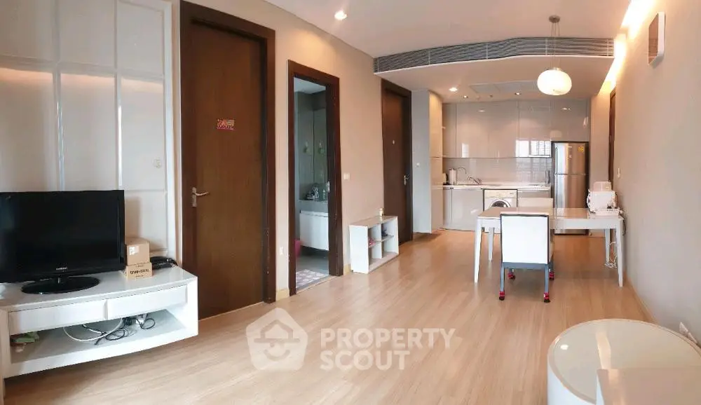 Modern open-layout living room with sleek kitchen, wooden flooring, and contemporary furniture.