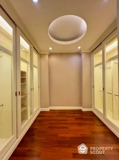 Luxurious walk-in closet with elegant wooden flooring and ample storage space.