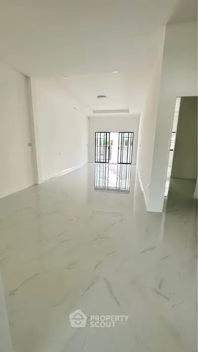 Spacious modern living room with glossy marble flooring and large windows for natural light.