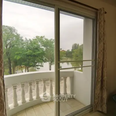 Charming balcony view with lush greenery and serene lake, perfect for relaxation.