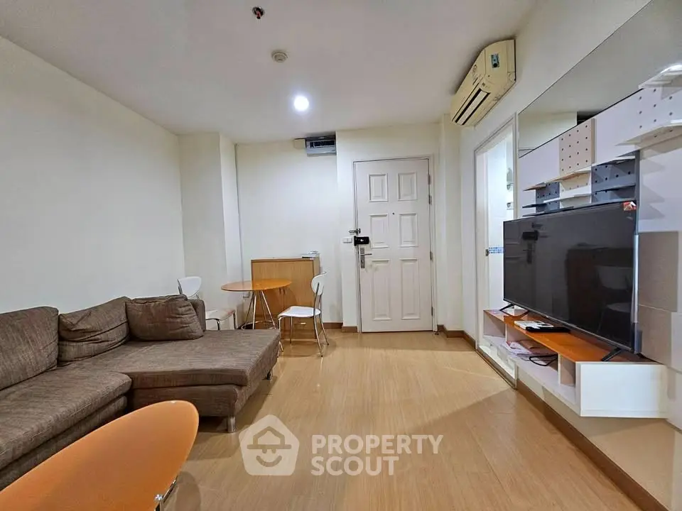 Modern living room with cozy brown sofa, wall-mounted TV, and stylish wooden flooring.