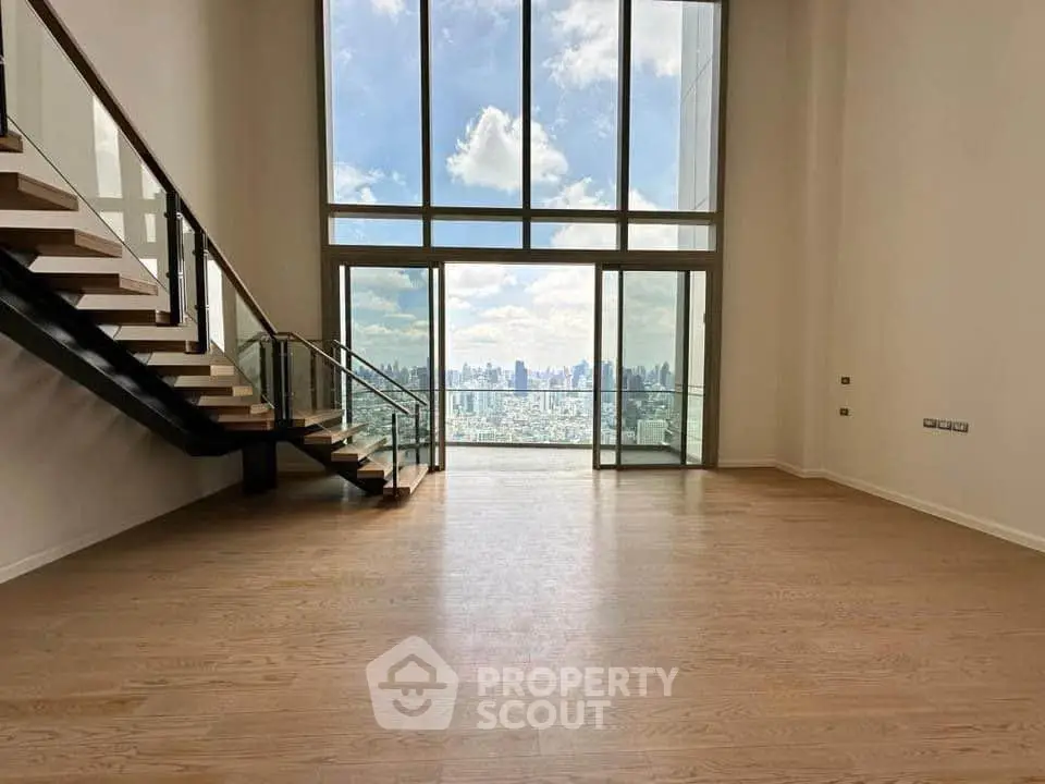 Spacious modern living room with floor-to-ceiling windows offering stunning city skyline views.