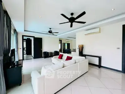 Spacious modern living room with white sofa and ceiling fans, perfect for relaxation.