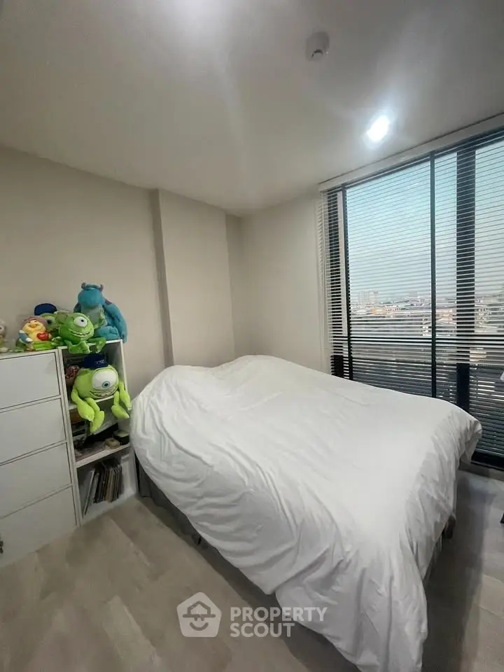Cozy bedroom with city view, featuring plush toys and modern decor.