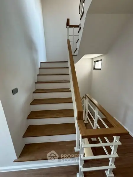 Modern staircase with wooden steps and sleek railing in a contemporary home.