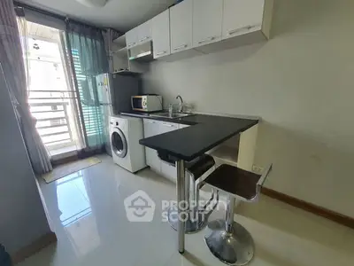 Modern compact kitchen with washing machine and breakfast bar in bright apartment.