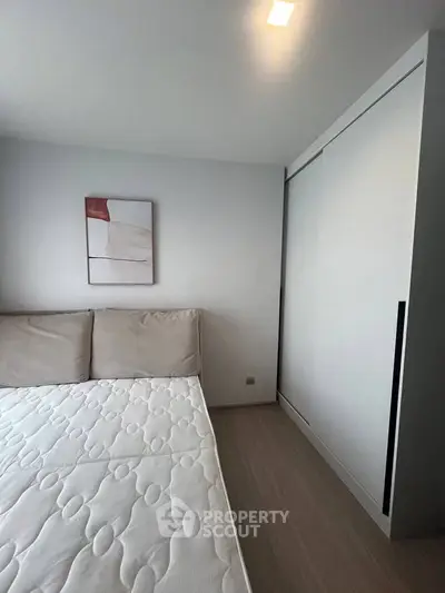 Modern bedroom with minimalist design featuring a comfortable bed and sleek wardrobe.