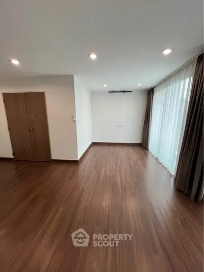 Spacious empty living room with wooden flooring and large windows