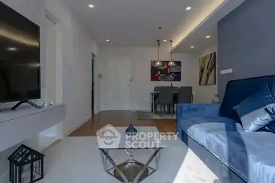 Modern living room with stylish decor and elegant dining area, featuring a sleek blue sofa and contemporary lighting.