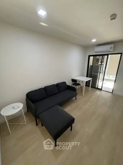 Modern living room with sleek black sofa and minimalist decor in a bright apartment.