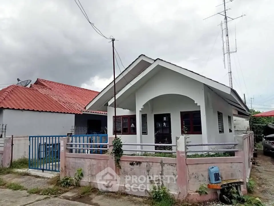 Charming single-story home with red roof and fenced yard, perfect for cozy living.