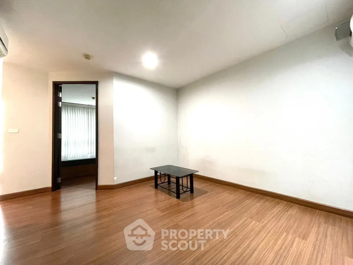 Spacious empty room with wooden flooring and minimalistic decor, perfect for customization.