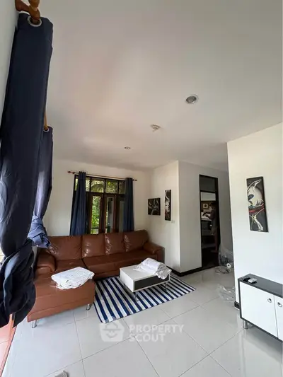 Spacious living room with modern decor and natural light, featuring a comfortable brown sofa and stylish accents.